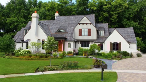 front of house with paver driveway and flower beds