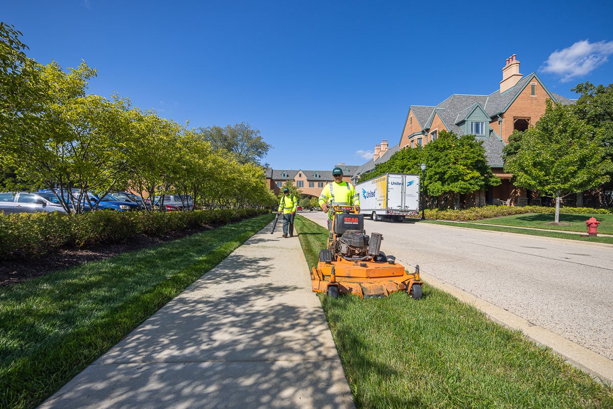commercial landscape maintenance retirement crew blowing off sidewalks and mowing
