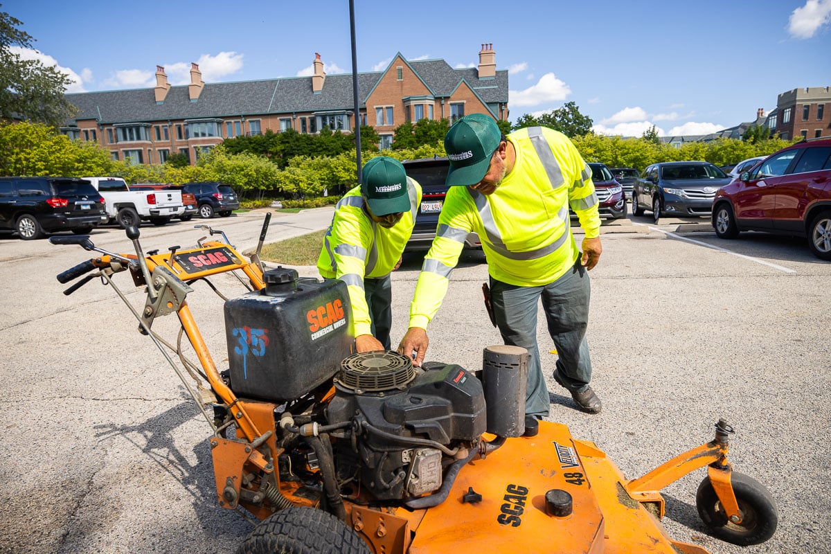 commercial landscape maintenance retirement crew looking at mower
