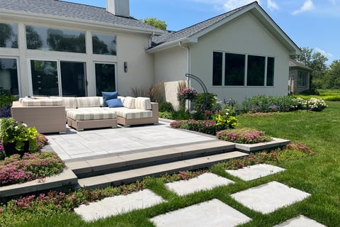 Residential backyard with stepper path stones leading to a seating area on the back patio