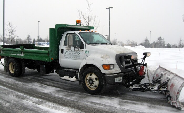 Snow truck plowing street while snowing