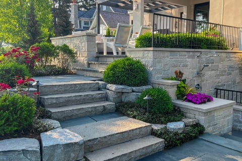 Stone step pathway leading around bushes and up to the stone patio