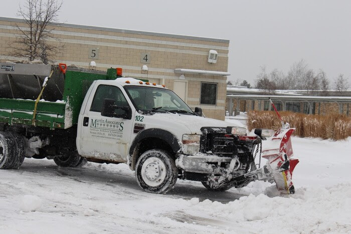 Truck plwong snow in parking lot