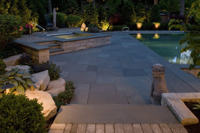 backyard pool and spa lit up at night with outdoor lighting
