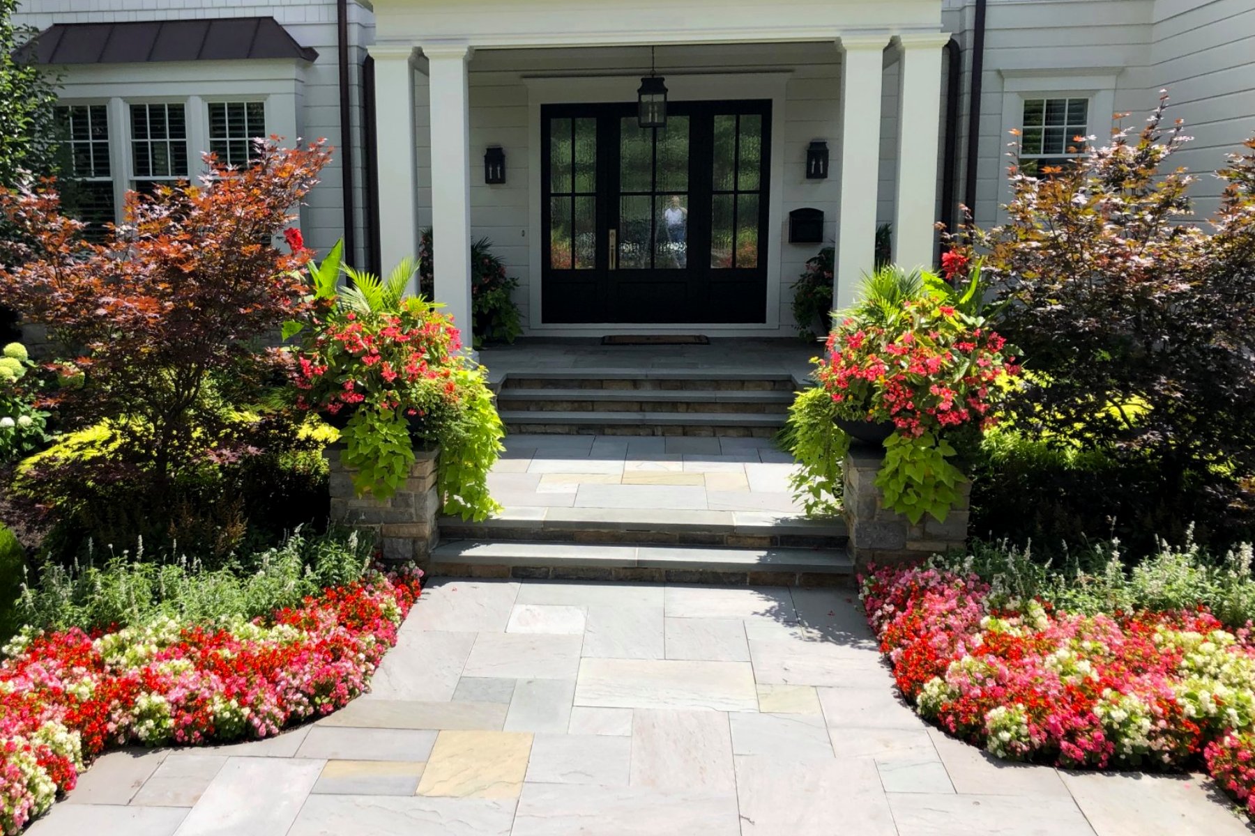 front door with long paver walkway and flowers