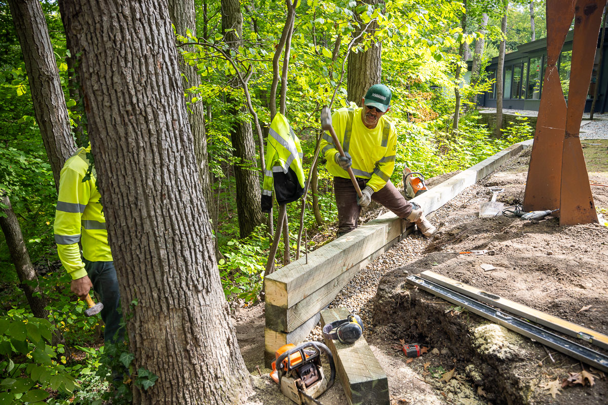 Residential landscape crew building wood plank retainer wall 