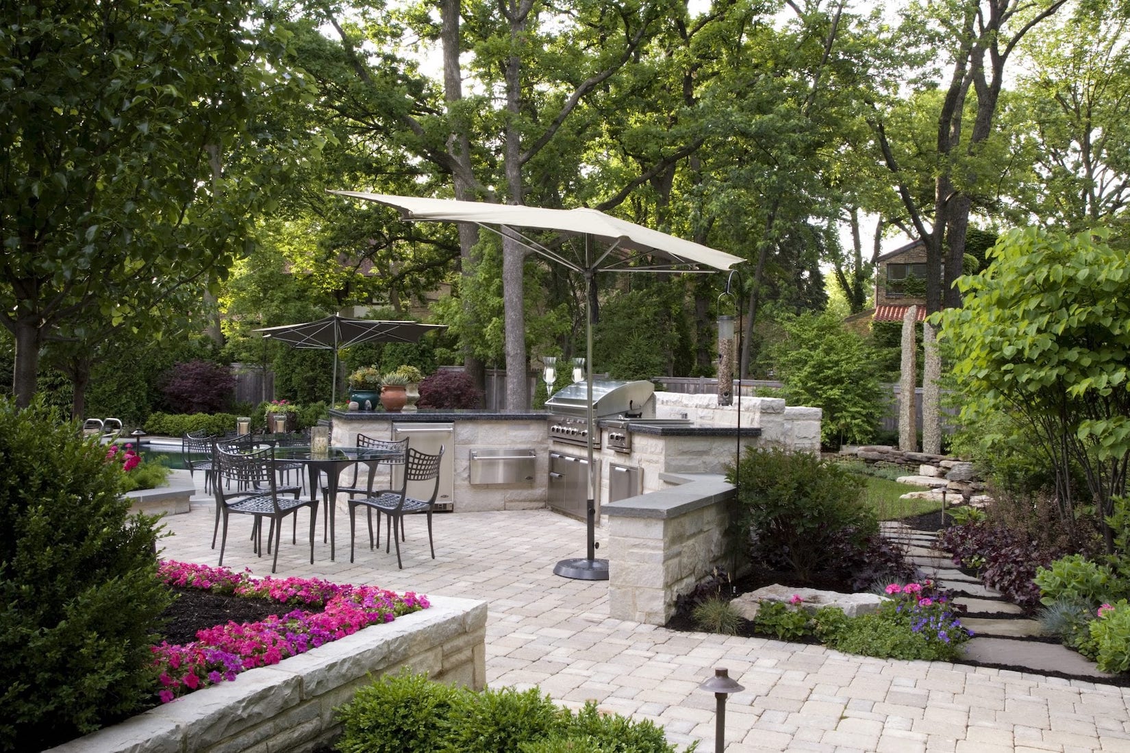 backyard kitchen with paver patio and raised flower beds