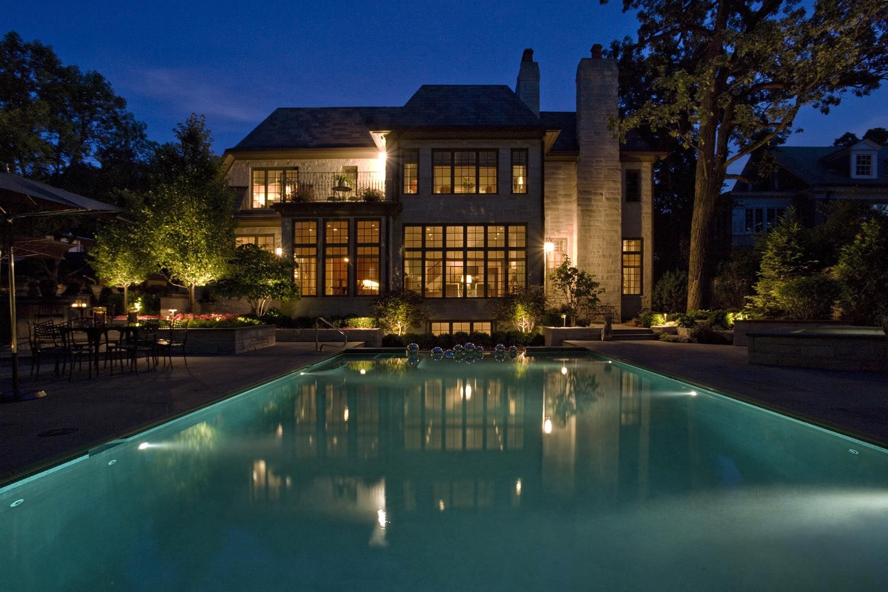 backyard pool lit up with outdoor lighting 