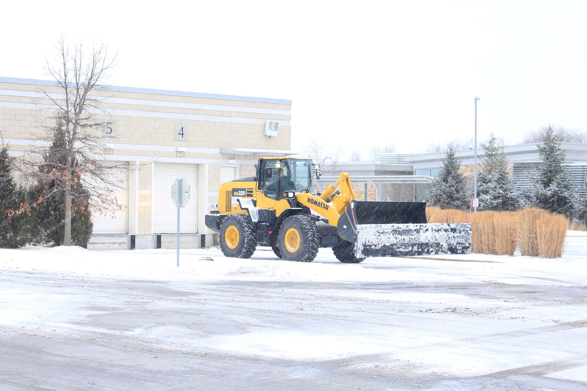 plow in snow storm clearing roads near business